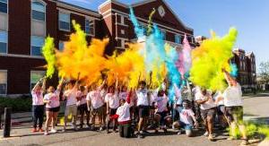 学生们在色彩赛跑后向空中投掷颜色.